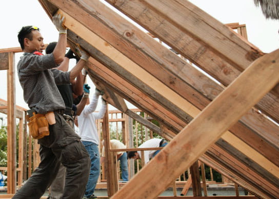 group of individuals putting up a frame as they build affordable housing.