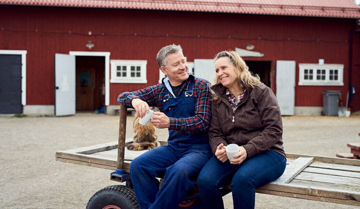 Person in overalls with another person sitting on barn door after closing on USDA rural home loan.