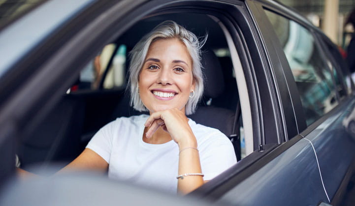 Smiling person with window down in car excited about finding good loan rates with BOK Financial. 