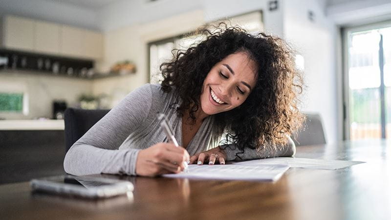 Woman signing paperwork at home